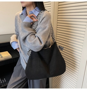 Black suede tote bag detail featuring a stylish black and white striped woven shoulder strap