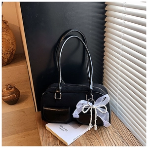 Detail of black vintage shoulder bag with white tulle bow and pearl chain charm