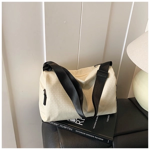 Detail of cream crossbody bag with geometric triangle pattern and wide black strap