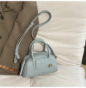Detail of light blue pebble leather bowling bag showing metal hardware and brand logo