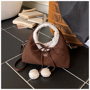 Détail du sac en daim marron avec bordure en laine d'agneau blanche et pompons doux