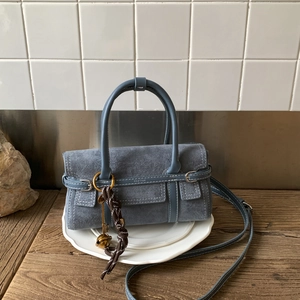 Detail of dusty blue matte suede handbag with gold key charm and top handles