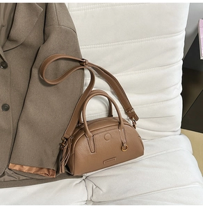 Close-up of brown pebbled leather texture and metal buckle on this bowling handbag