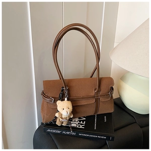 Détail du sac Boston en daim marron avec de longues anses et un charm d'ours en peluche