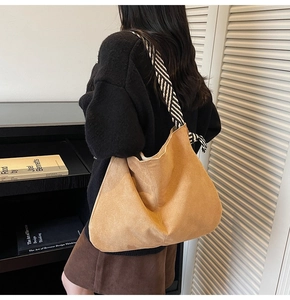 Detail showing high-capacity tan suede tote bag with black and white twill shoulder strap