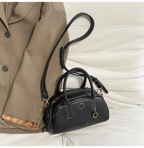 Detail of black pebbled leather handbag with contrast white stitching and gold hardware