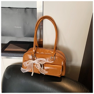 Detail of caramel leather Boston bag with white lace bow and pearl charm ornament