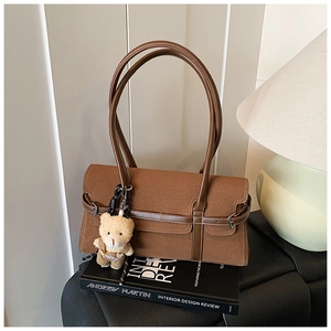 Détail du sac Boston en daim marron avec garniture en cuir et porte-clés ourson