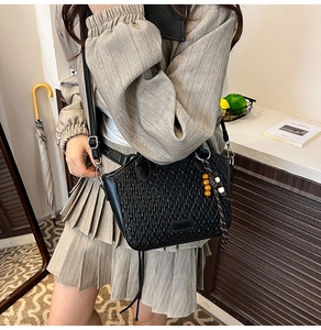 Detail of black woven texture bucket bag with colorful wooden beads and leather strap