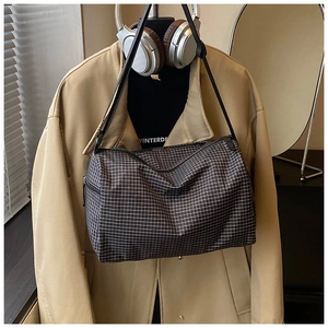 Detail of the checkered crossbody bag featuring a black zipper and adjustable strap