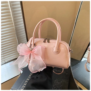 Détail du sac bowling en cuir verni rose clair avec grand nœud en organza et perles