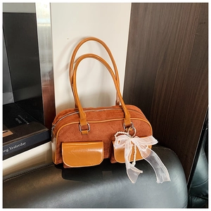 Detail of vintage brown suede shoulder bag featuring leather pockets and a bow charm
