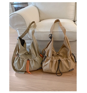 Detail view of khaki and beige drawstring tote bags showing adjustable straps on a wood floor