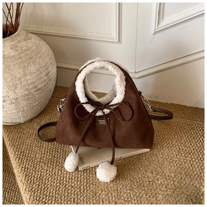 Détail du sac en daim marron foncé avec bordure en peau lainée et pompons