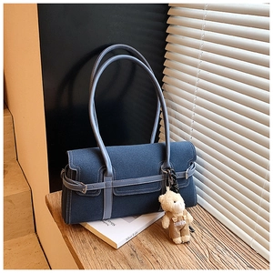 Détail du sac Boston en denim bleu foncé avec bandoulière et pendentif ours mignon