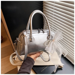 Détail du sac Boston argenté avec nœud en organza blanc et pendentif en perles