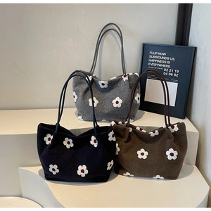 Detailed view of plush tote bags in three colors with white floral patterns and leather straps