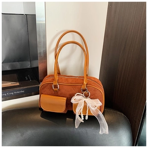 Detail of caramel suede tote bag featuring mini pockets and a white pearl bow charm