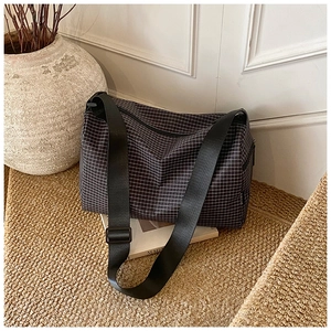 Detail of the gray plaid crossbody bag featuring adjustable wide shoulder strap and zipper