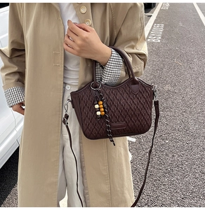 Detailed close-up of dark brown bucket bag featuring embossed woven texture and colorful beads