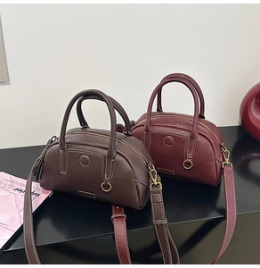 Detailed macro view of litchi grain leather texture on classic Boston style handbags