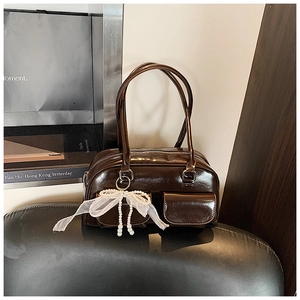 Detail of dark brown vintage bowling bag with pearl bow charm and twin front pockets