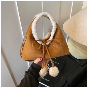 Détail du sac en daim caramel avec bordure en laine d'agneau et cordons à pompons blancs