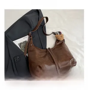 Détail du sac hobo en cuir marron foncé vintage avec franges et breloque ours en peluche