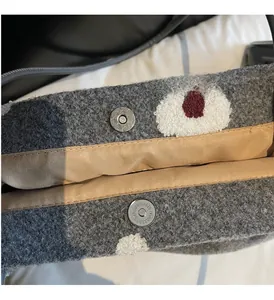 Detail of grey tweed tote bag with floral embroidery and matte silver magnetic clasp
