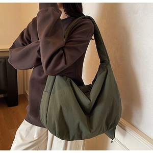 Detail einer dunkelgrünen Stofftasche mit strukturierter Oberfläche und breitem Gurt