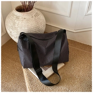 Detailed close-up of a black and white checkered pillow bag with wide nylon strap