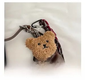 Gros plan d'un bijou de sac ours en peluche marron avec chaîne et mousqueton sur un cabas