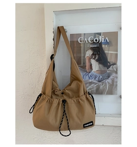 Detail of khaki nylon crossbody bag showing the drawstring design and black fashion label