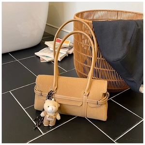 Détail du sac Boston en daim caramel avec lanière en cuir et pendentif ours de mode