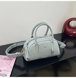 Detail of light blue lychee pattern leather bag with dual handles and gold hardware