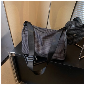 Detail view of the black and white checkered pattern fabric and durable nylon shoulder strap