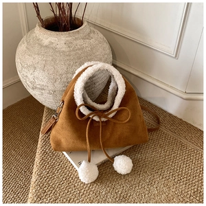 Gros plan d'un sac en daim marron avec bordure en fausse fourrure blanche et un nœud