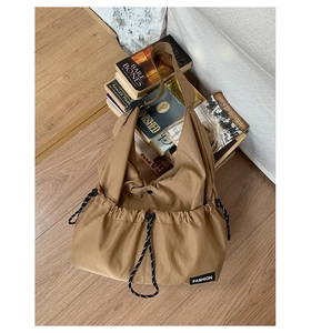 Detailed view of khaki nylon drawstring tote bag with fashion label on wooden floor