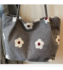 Detail of grey plush tote bag with 3D red and white floral patterns and soft fabric texture