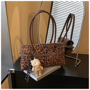 Détail d'un sac bandoulière léopard avec sangle en cuir et charmant porte-clés ours