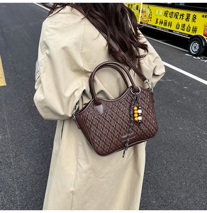 Detail of dark brown woven texture bucket bag with beaded charm on street model