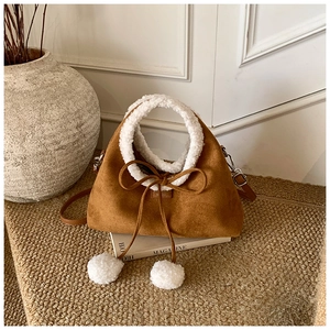 Détail du sac en suédine marron avec bordure en polaire blanche et pompons décoratifs