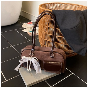 Close-up of vintage brown suede tote with faux leather trim and pearl bow charm detail