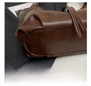 Détail du fond de sac en cuir synthétique marron foncé avec coutures de précision