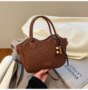 Close-up of brown woven bucket bag with wood bead charm and silk scarf details