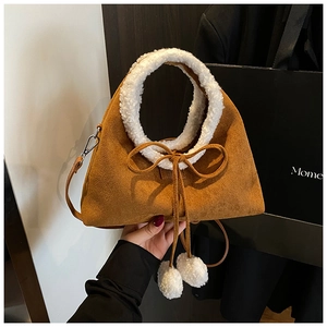 Détail du sac en daim marron avec poignée en peluche blanche et pompons décoratifs