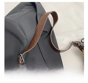 Détail de la bandoulière en cuir marron et boucle argentée sur un grand sac cabas gris foncé