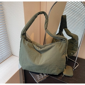Detailansicht der olivgrünen gesteppten Hobo-Tasche mit passendem Münzbeutel auf dunklem Tisch