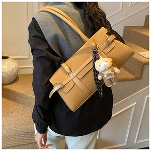 Détail du sac Boston marron avec bandoulières réglables et breloque ours sur un mannequin