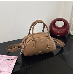 Detail of brown litchi pattern leather bowling bag with gold hardware and logo plate